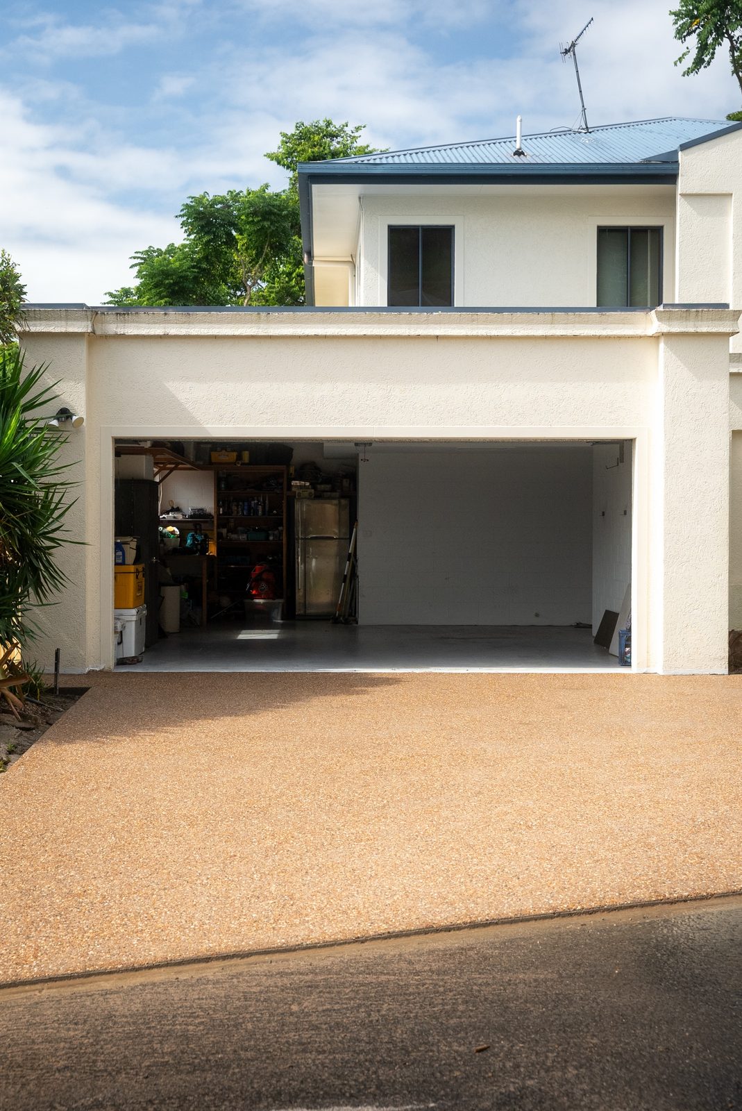 Finished exposed aggregate driveway leading up to an open double garage