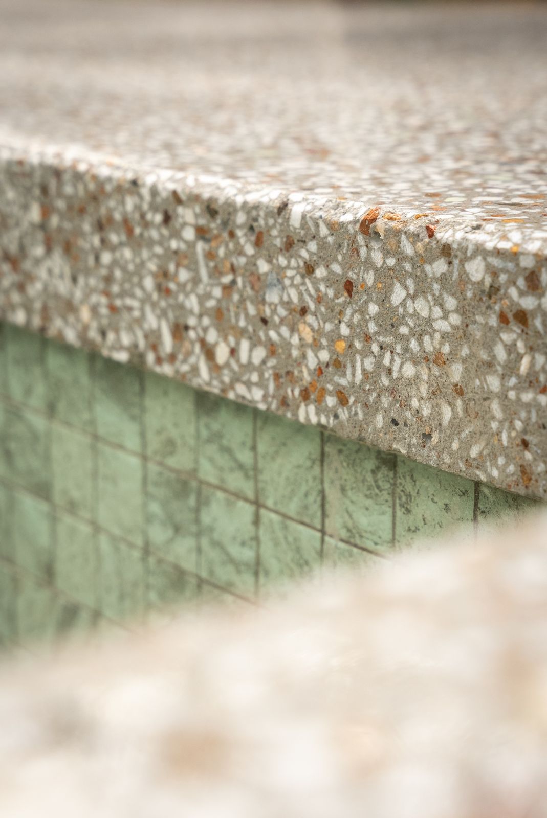 Close-up of a honed concrete coping edge showing the stone