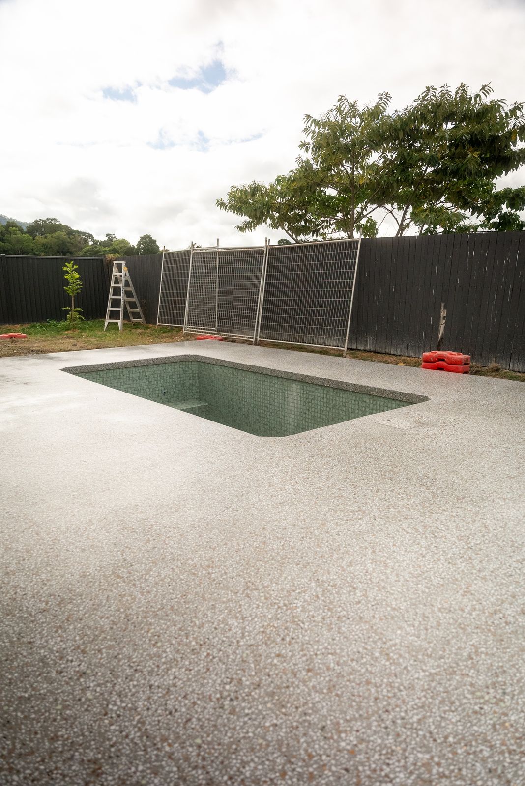 Light exposed aggregate surround and coping around a green-tiled pool